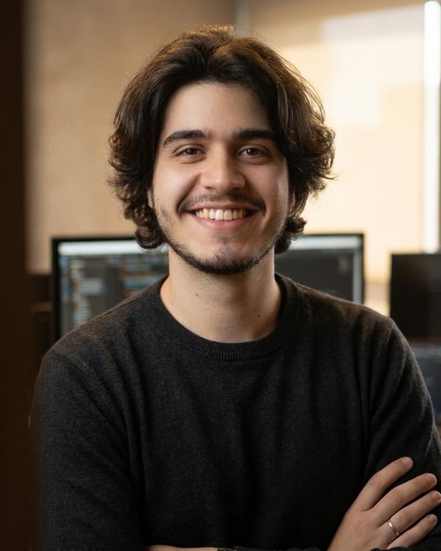 Matheus Fidelis, de suéter preto, sorrindo